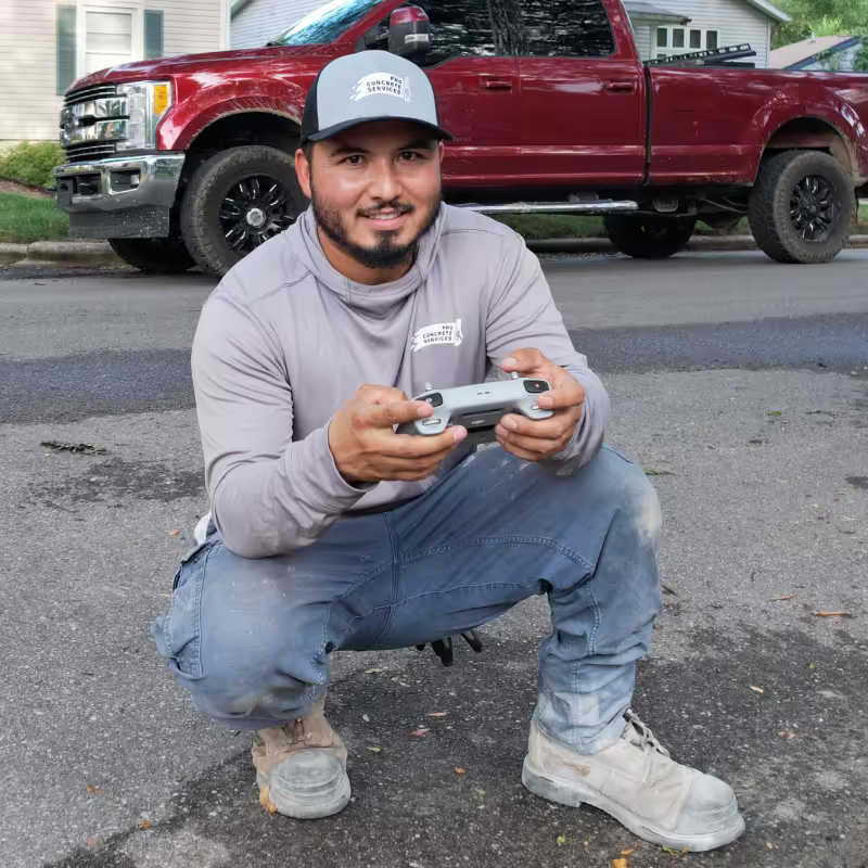Jose Escamilla, owner of Pro Concrete Services, holding a drone controller on a job site in Grand Rapids, MI
