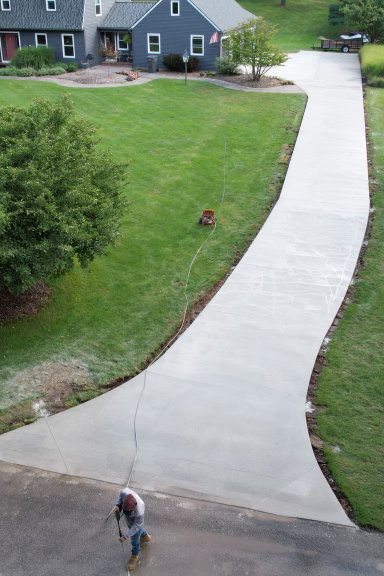 Aerial view of long curved concrete driveway with sealer application at rural residential property, Grand Rapids MI