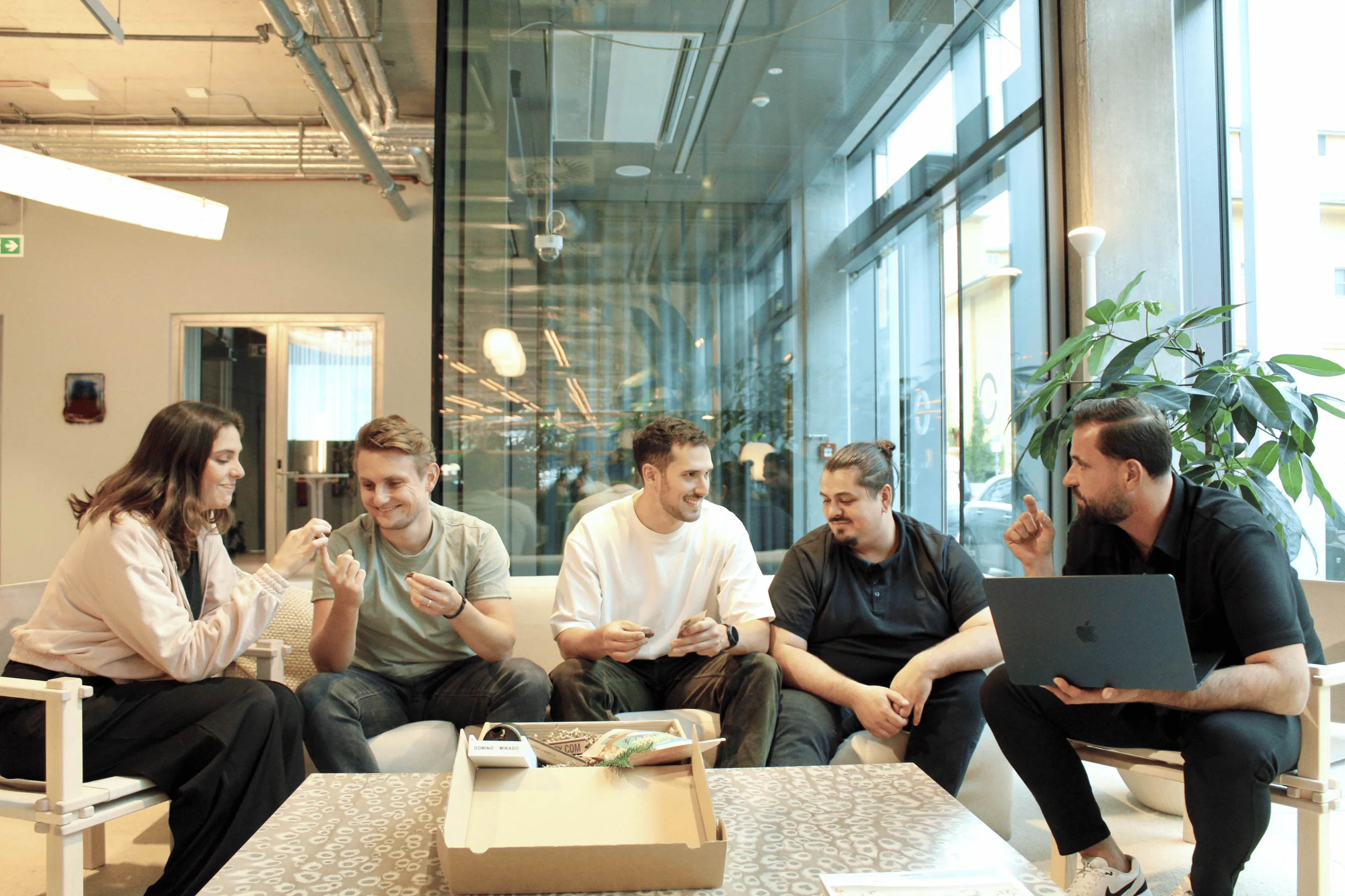Team von GIVEAJOY in Berlin bei der gemeinsamen Arbeit im modernen Büro – kreative Köpfe eines Start-ups für nachhaltige Geschenkboxen und individuelle Mitarbeitergeschenke für Unternehmen.