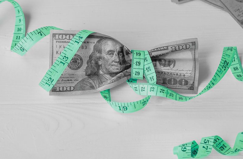 Image representing the article how to calculate your true cost of capital with a measuring tape tied to 10 $100 bill. 