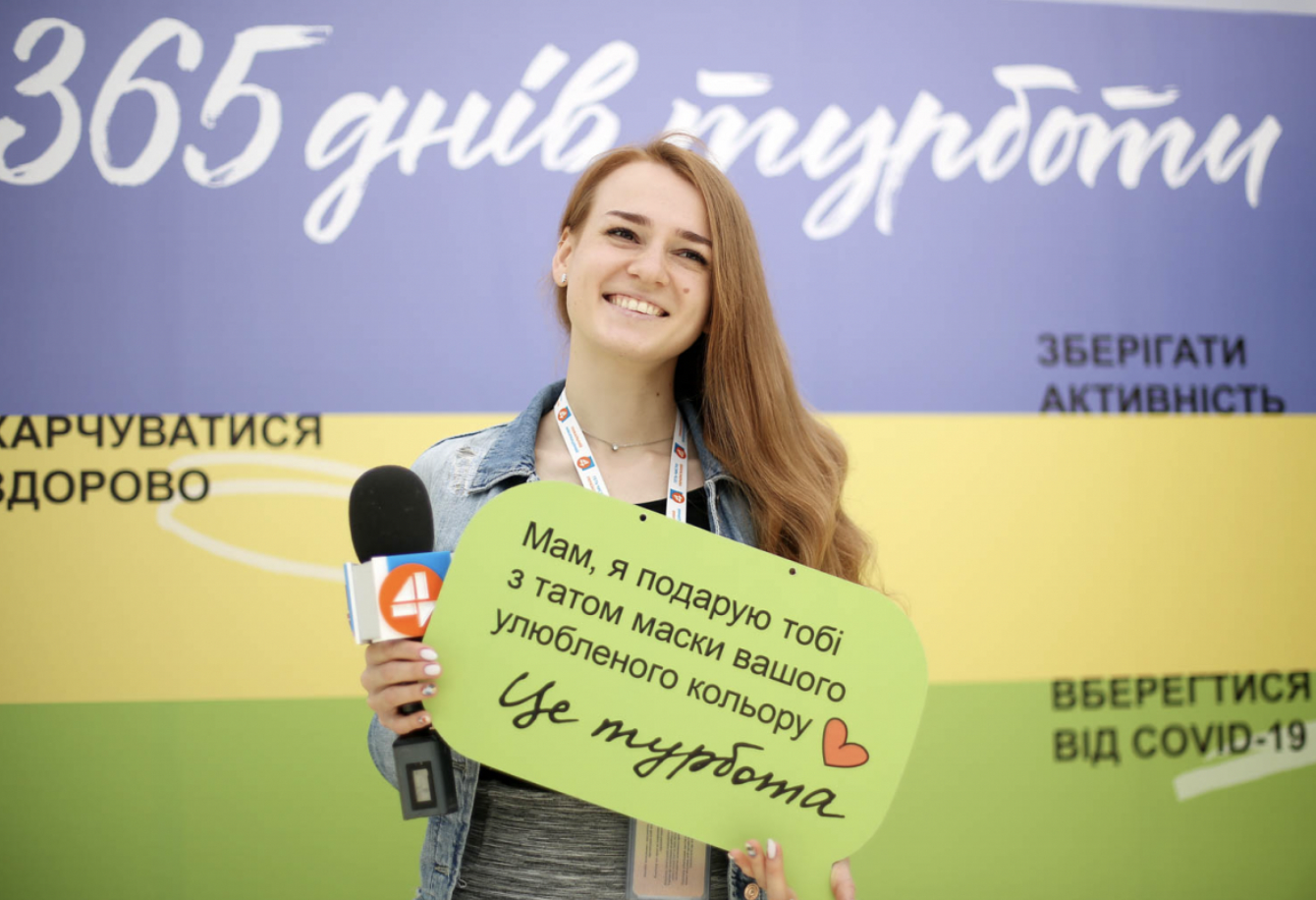 A woman is holding a poster of the One Care project.