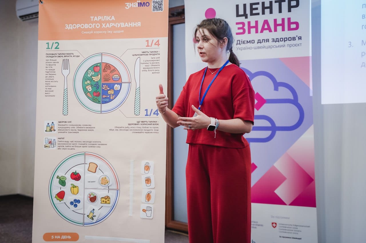 Жінка говорить на фоні банерів