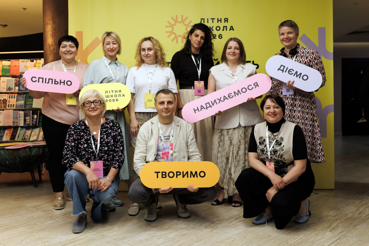 Спільне фото команди проєкту "Діємо для здоров'я" на фоні банеру літньої школи. 