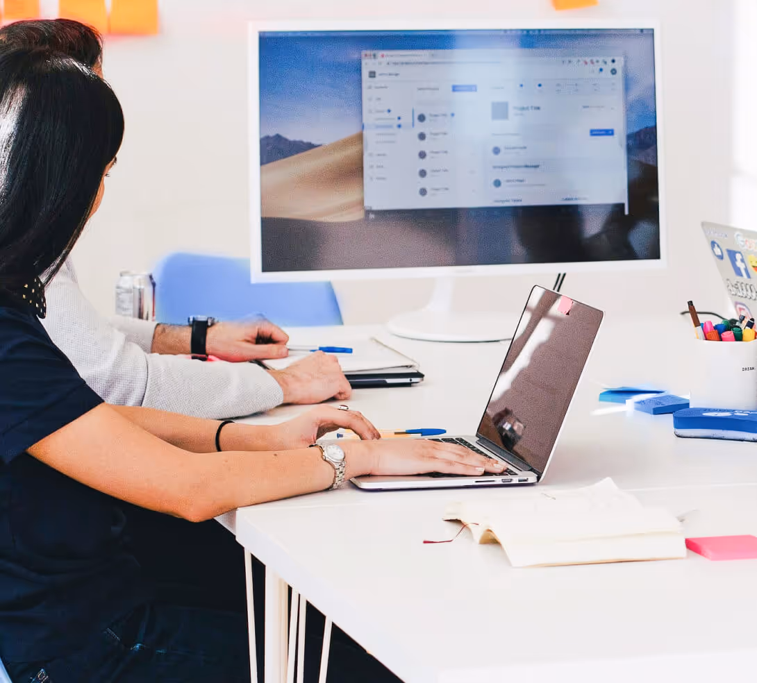 A group of diverse individuals seated at a table, each using a laptop for collaborative work or discussion.