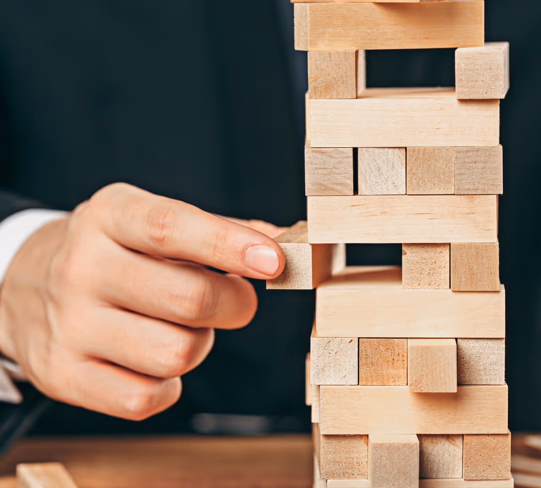 A man is engaged in play, stacking colorful wooden blocks on a table.