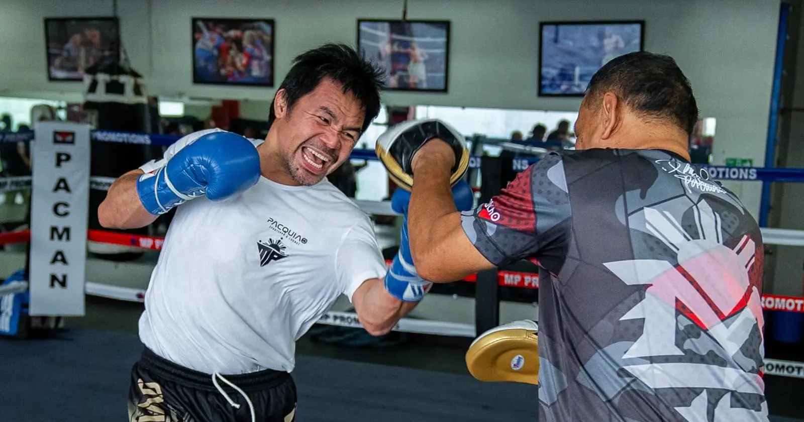 Manny Pacquiao throws a punch with blue gloves during an intense boxing training session in the gym.
