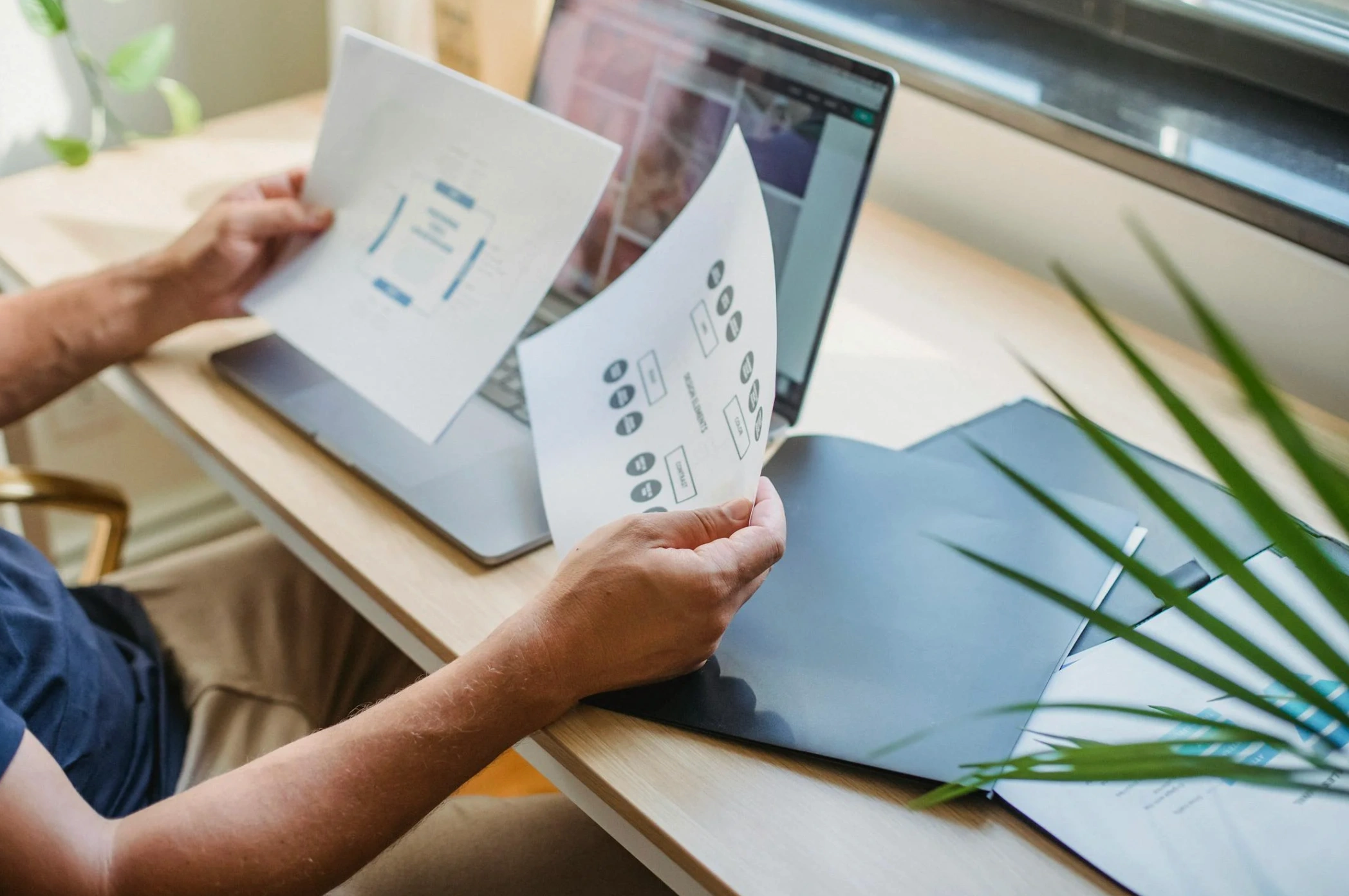 man looking at notes while working on laptop