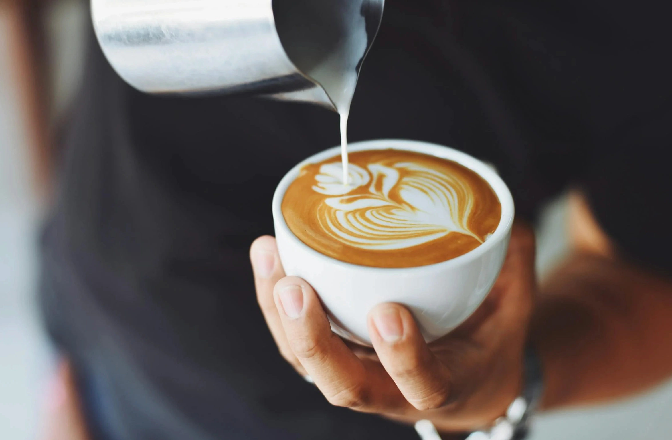 Man pouring milk on coffee