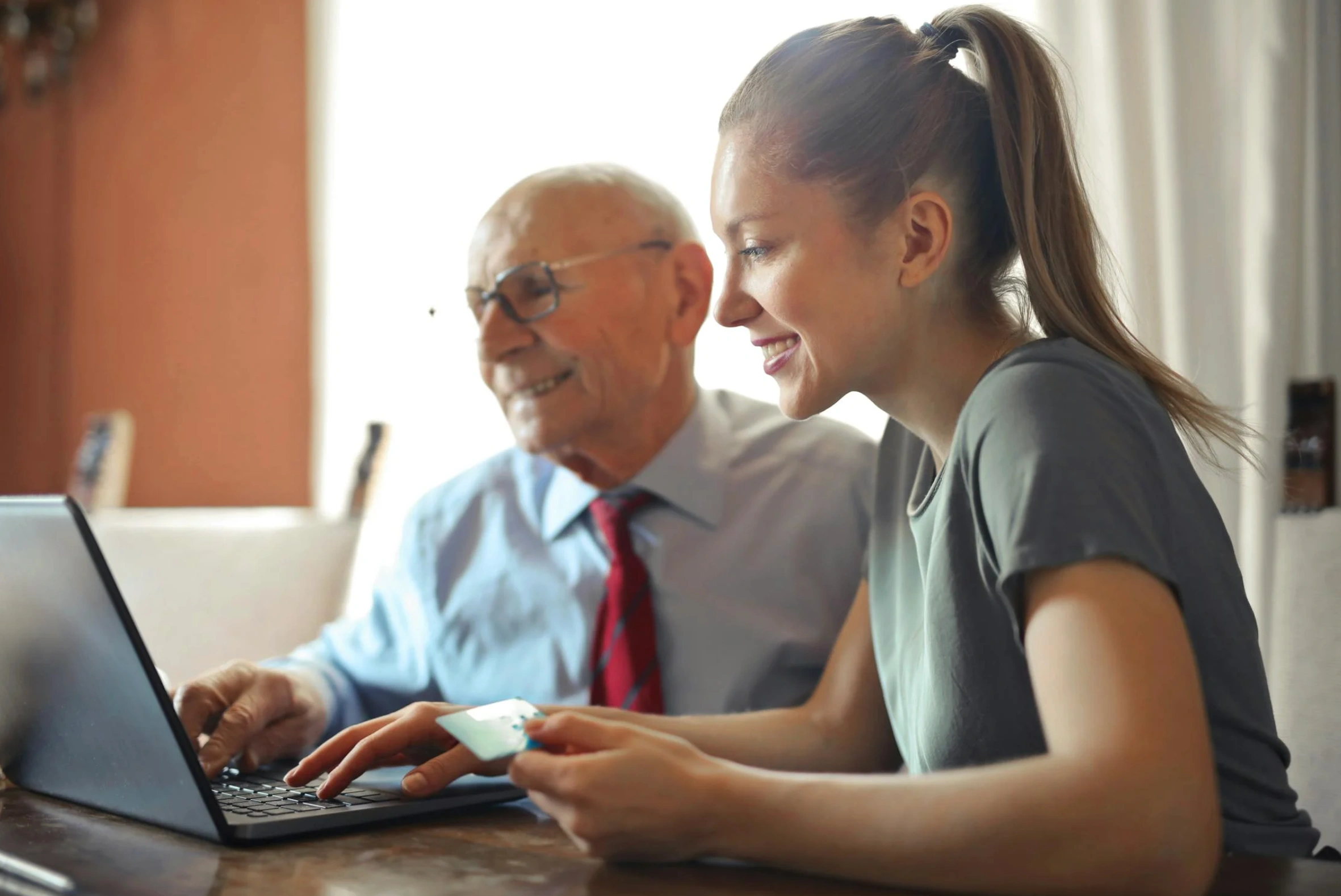 senior man with young woman making online purchase