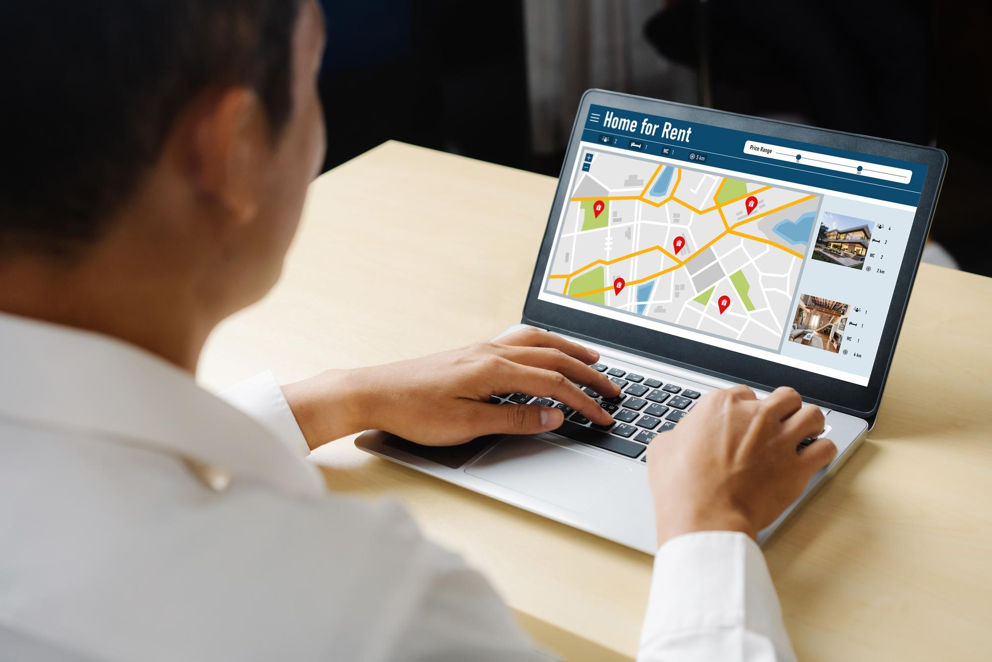 Overhead view of a computer workspace showcasing an online rental real estate search interface with highlighted map pins and listings, symbolizing hyperlocal SEO targeting for property seekers