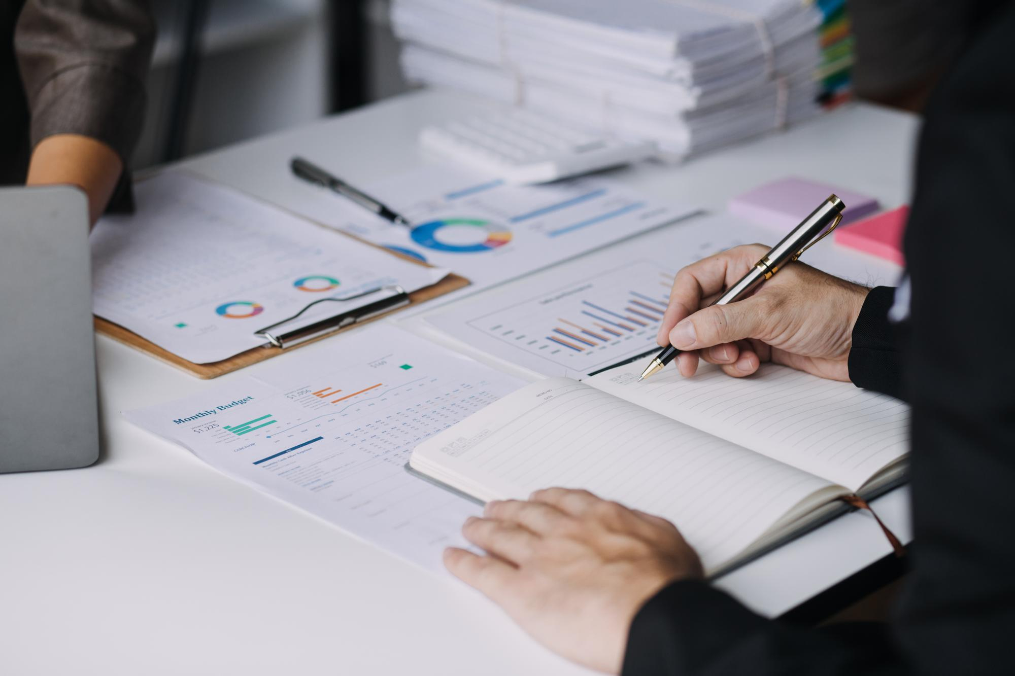 Financial analysts reviewing business financial reports on a digital tablet during a corporate meeting, planning investment projects and discussing successful teamwork results