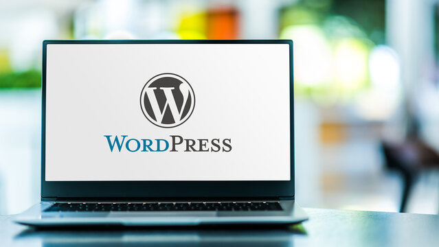 WordPress logo displayed on laptop screen in modern office environment.