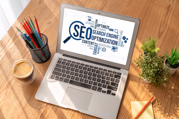 SEO search engine optimization word cloud displayed on laptop screen at desk with coffee and plants.
