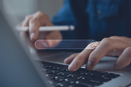 Person using laptop and smartphone with a glowing search bar overlay representing online search.