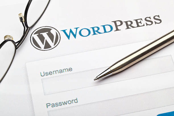 WordPress login page with username and password fields, pen and glasses on desk.