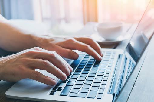 Person typing on laptop keyboard while working on digital marketing strategy.