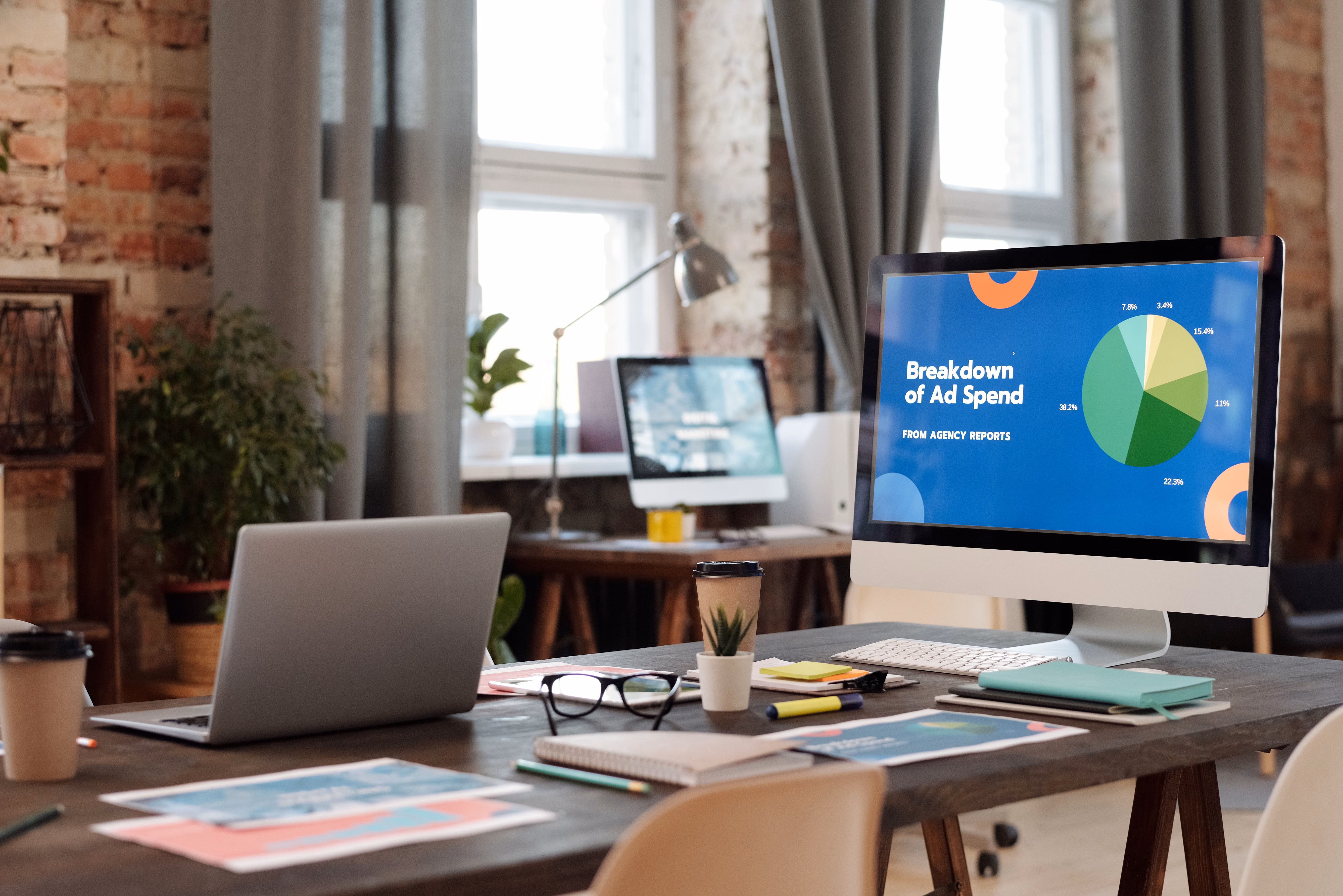 Ad spend breakdown pie chart displayed on a desktop monitor in a loft office