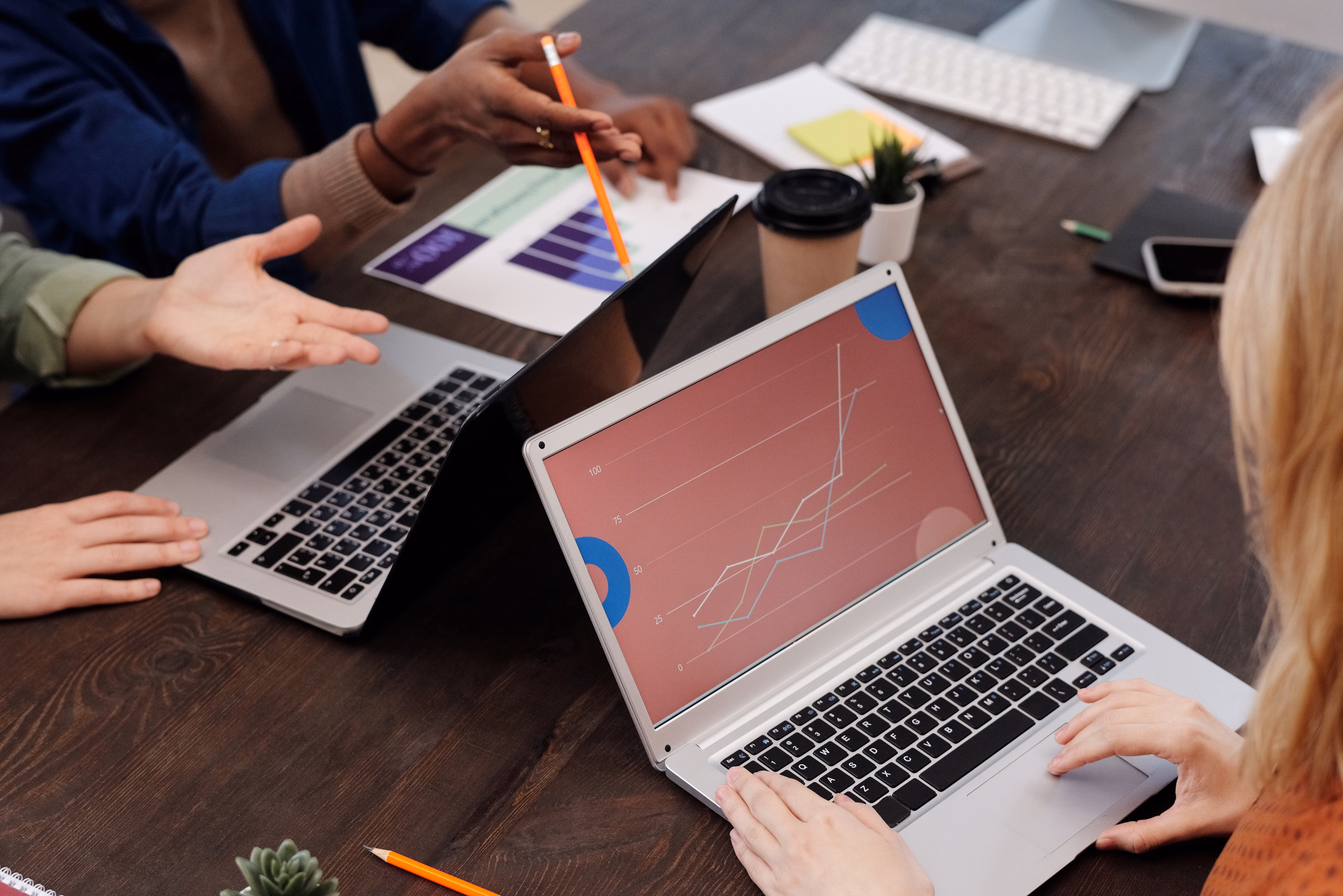 Growth trend lines shown on laptop screen during a team discussion with charts