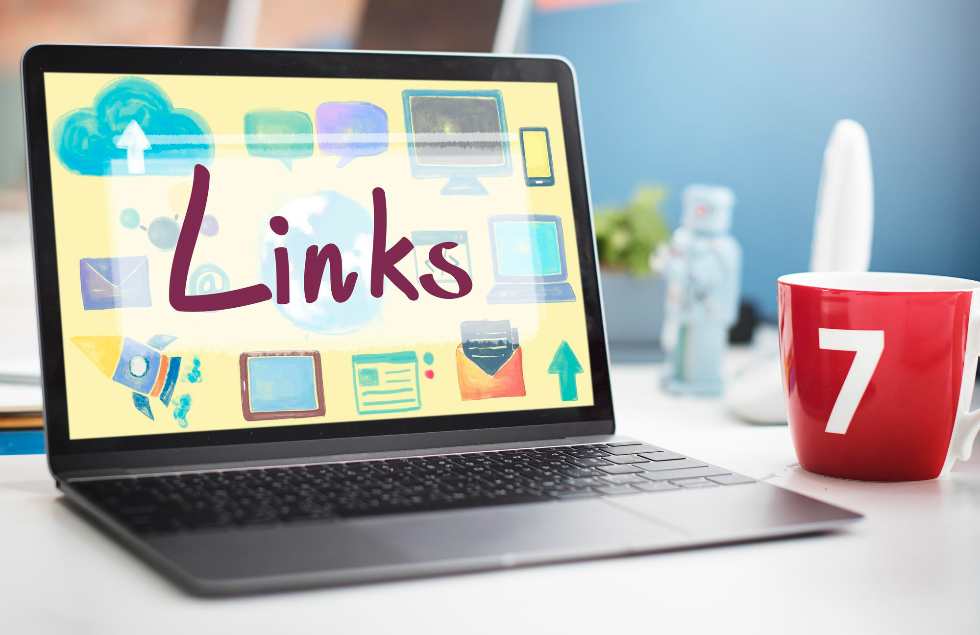 Laptop on a desk showing Links in script among watercolour web and device icons, beside a red mug, illustrating a link-building theme.