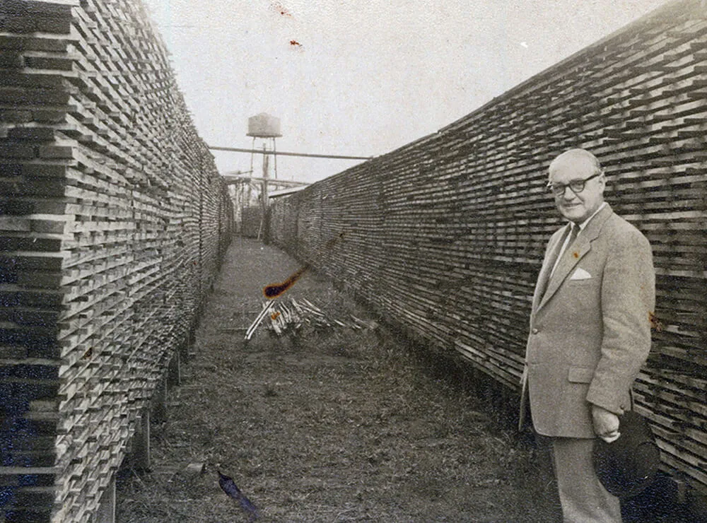 1960's Lambert Hyne standing in front of a row of treated timber packs.