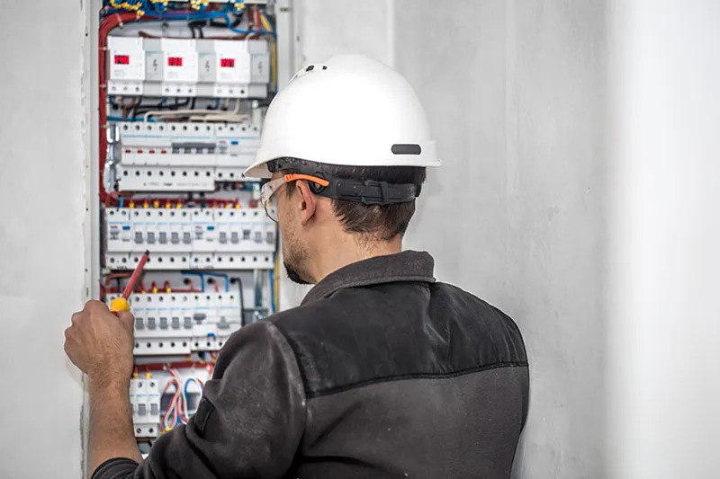 Electrician working on wires of switchboard
