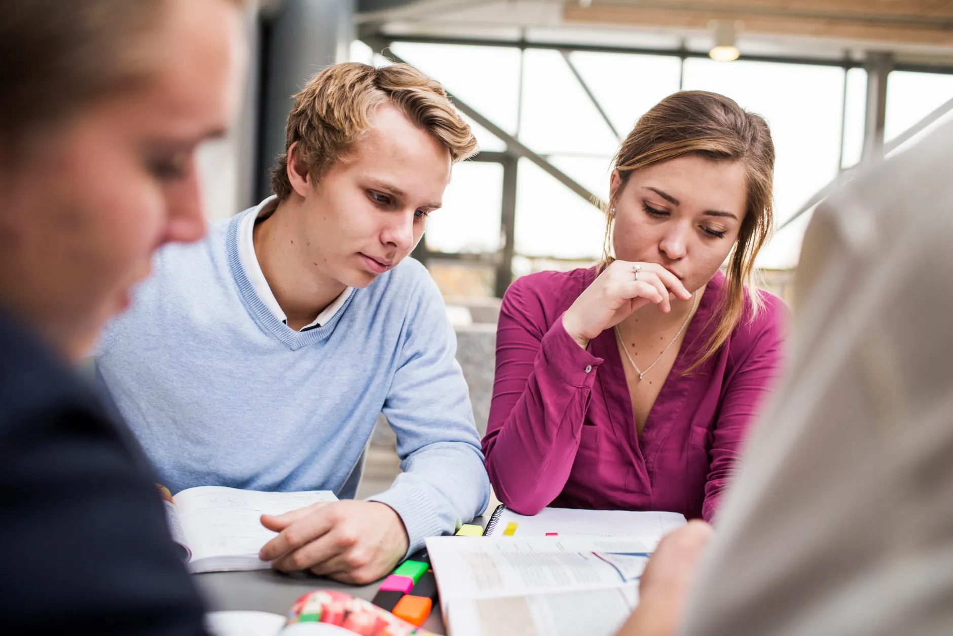 Studenten sitzen gemeinsam über Büchern und lernen.