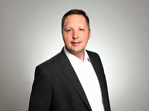 Foto von Hendrik. Lächelt in die Kamera.