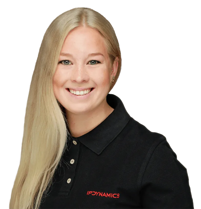 Porträt einer lächelnden Frau mit langen blonden Haaren in einem schwarzen Poloshirt mit rotem IP Dynamics-Logo.