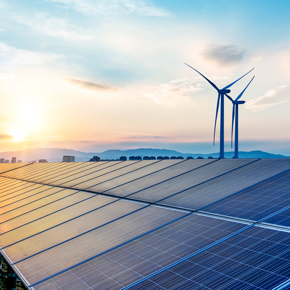 Solaranlage und Windräder erzeugen erneuerbare Energie vor Bergkulisse im Sonnenuntergang