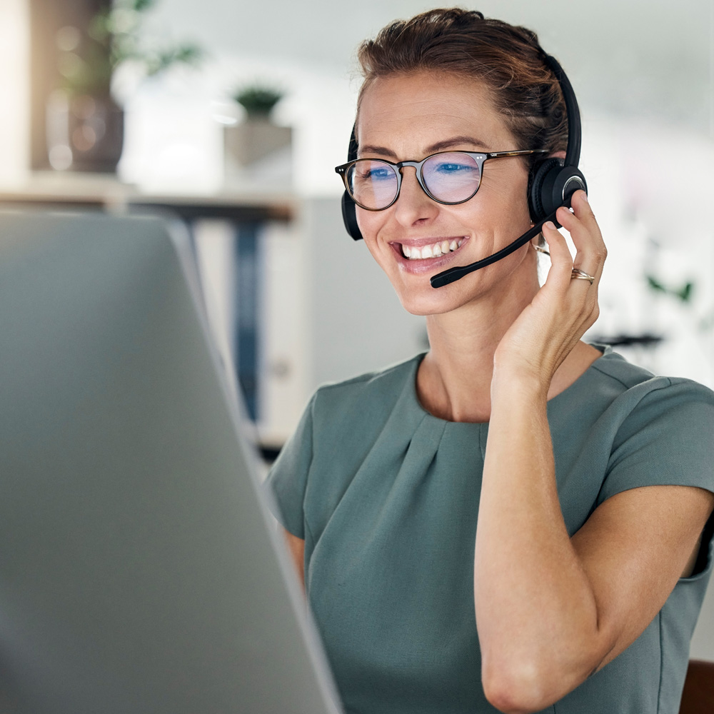 Mitarbeiterin mit Headset am Laptop im Kundenservice