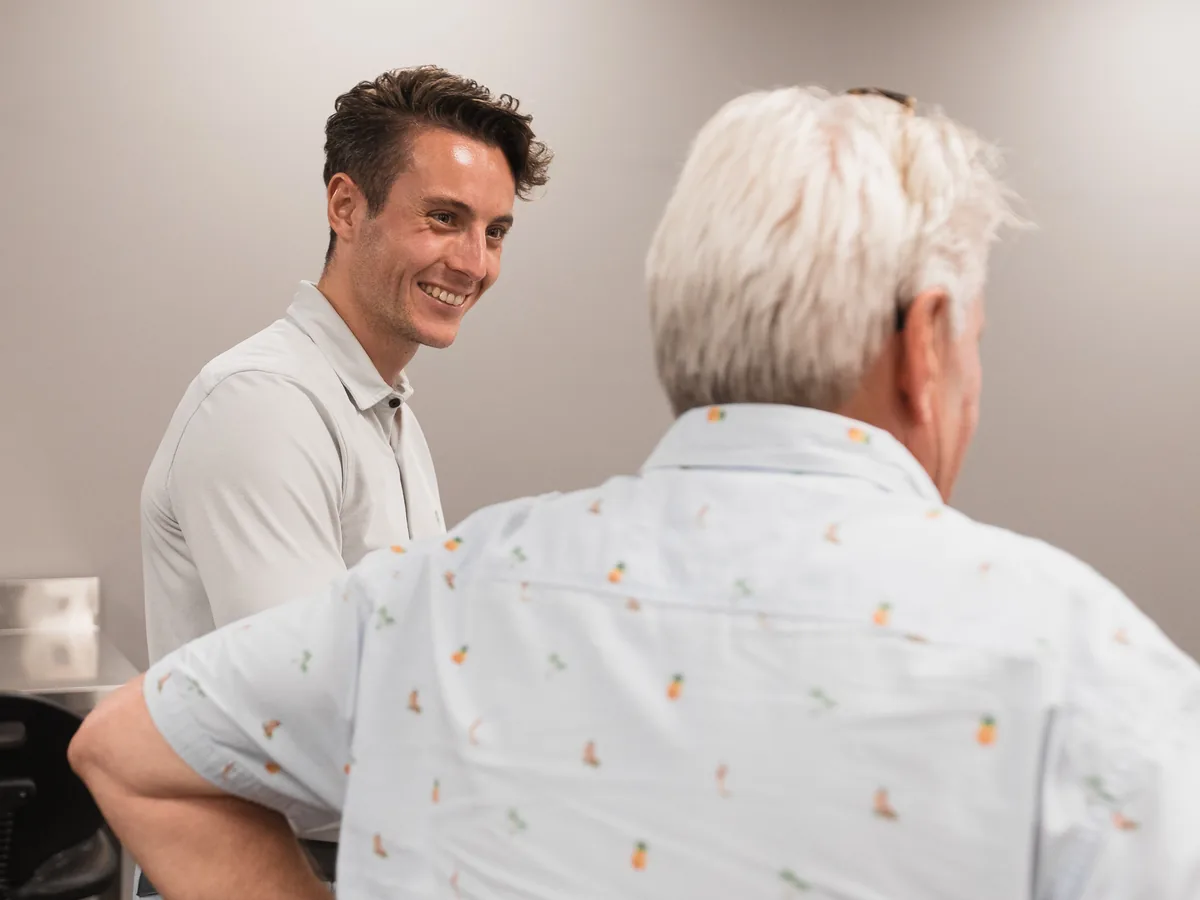 Smiling young colleague talking with a senior colleague in a workspace
