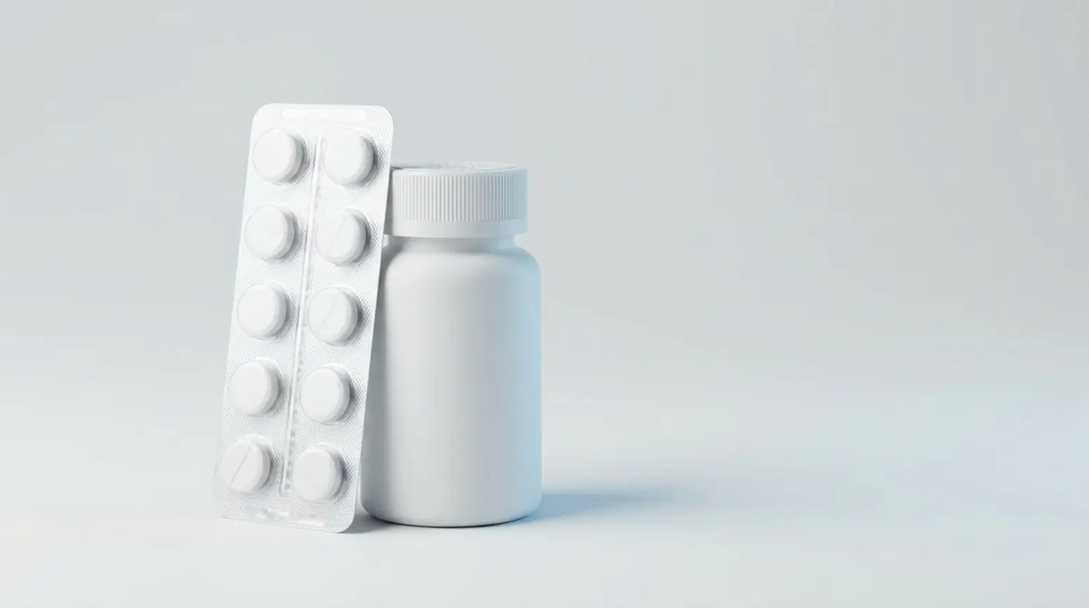 A clear blister pack with tablets beside a white pill bottle on a grey background.