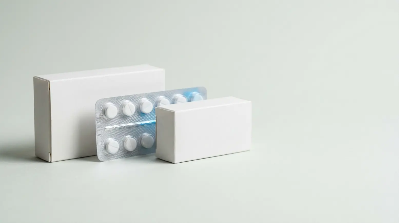 Clean pharmaceutical packaging development sequence on a pale grey surface, showcasing mockups.
