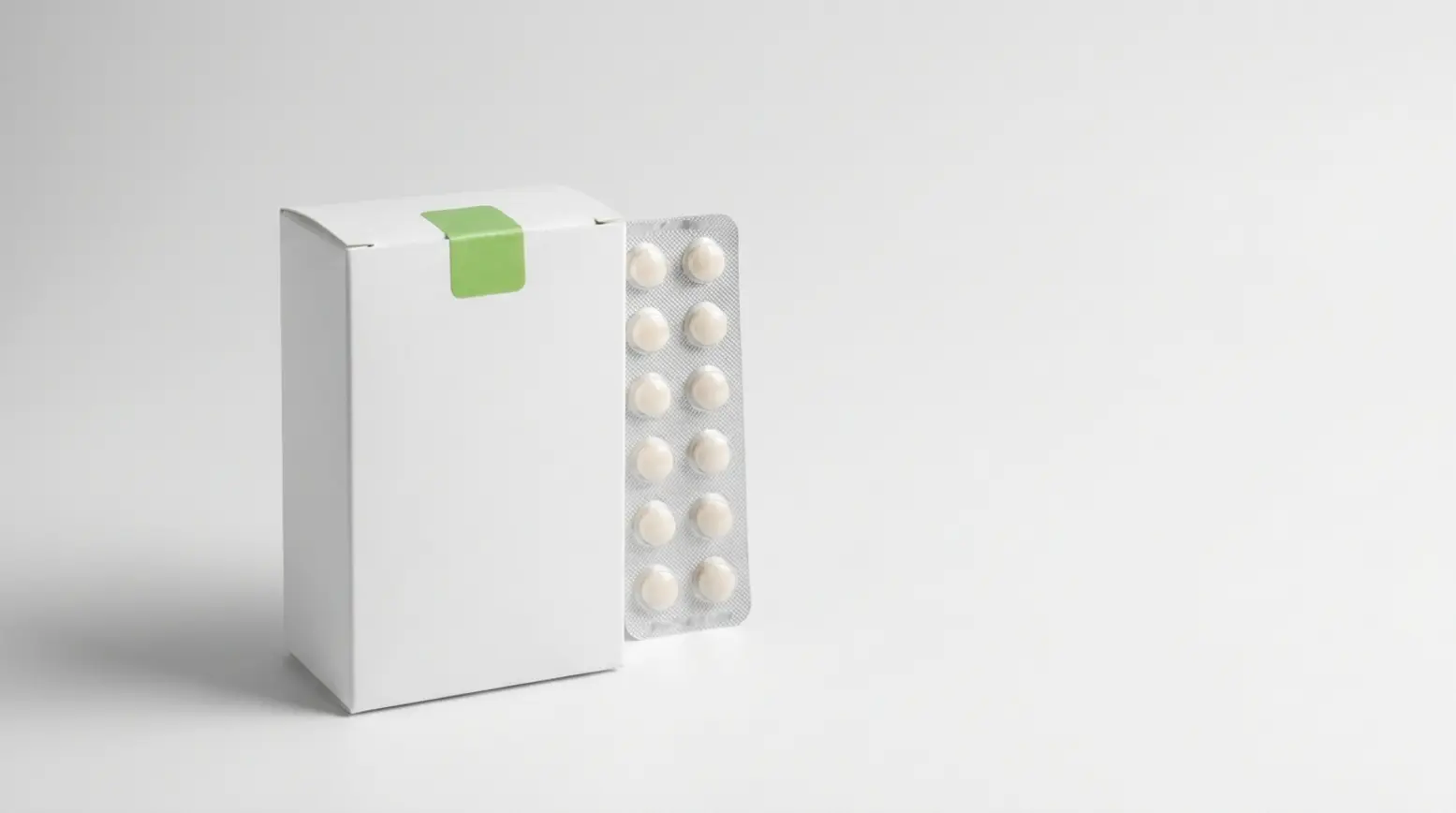 A clean, photorealistic arrangement of a medicine carton, blister pack, and quality-control tab.