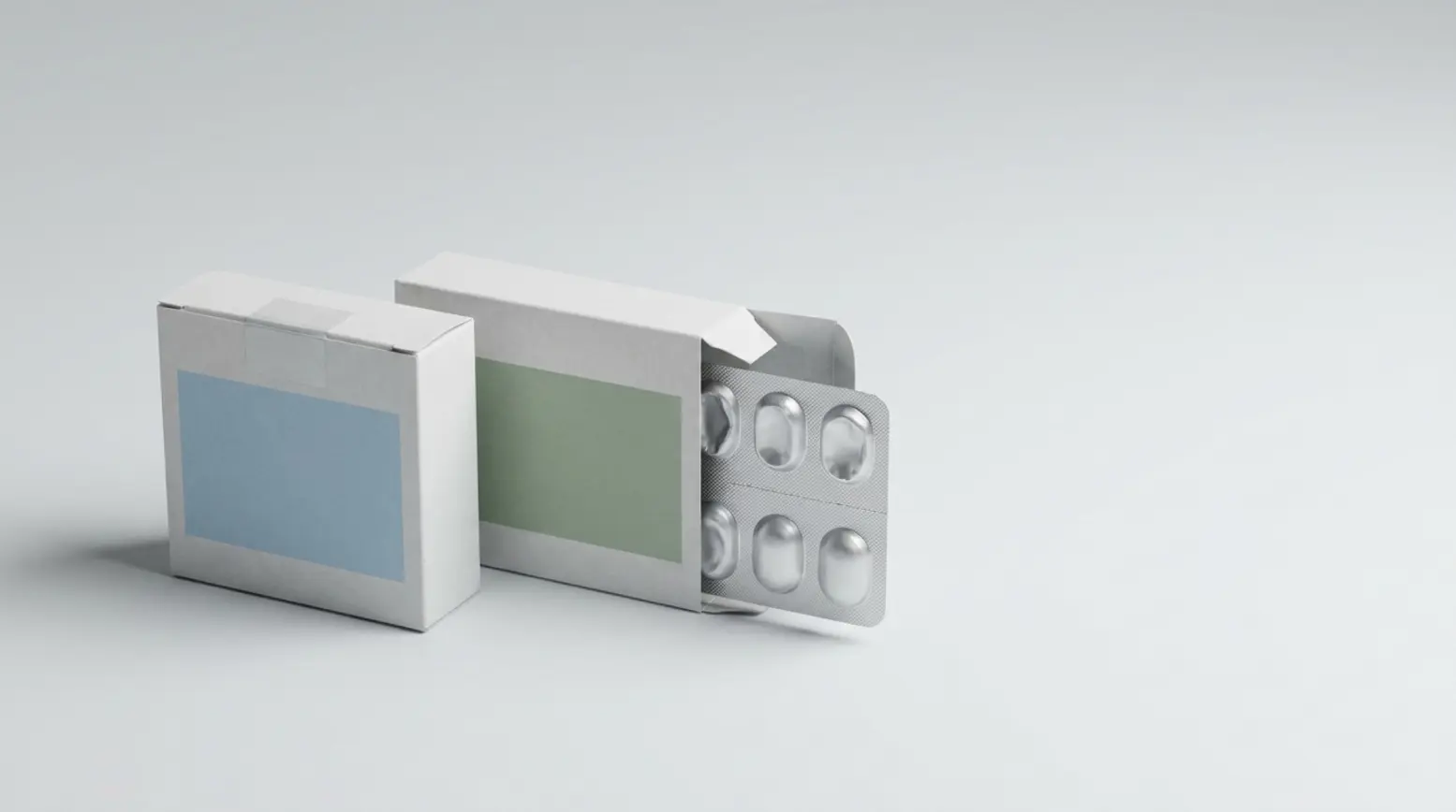 Two similar unbranded pharmaceutical cartons with distinct colors and seals on a grey surface.