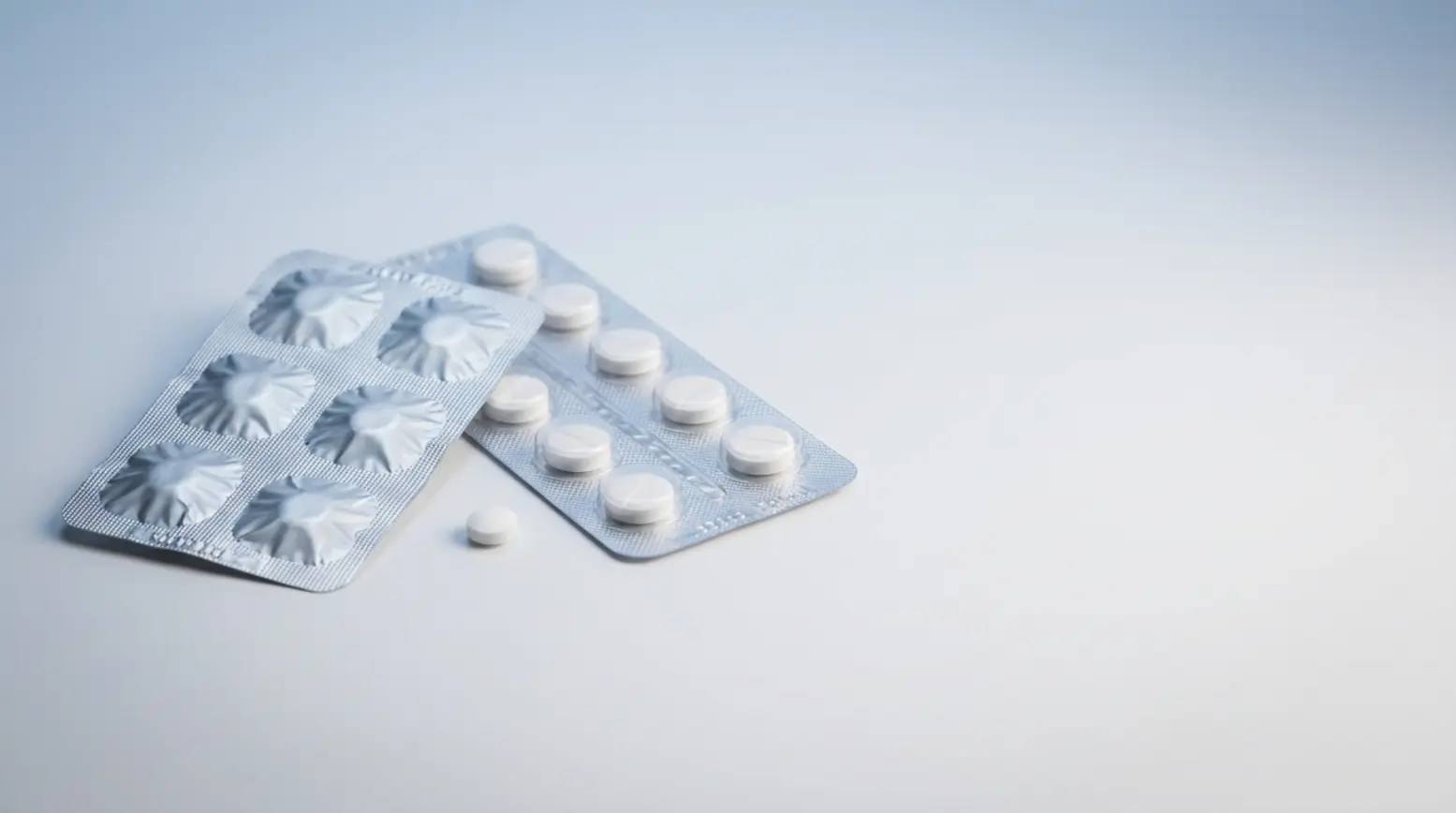 Two pharmaceutical blister packs showcase packaging details on a clean studio surface.