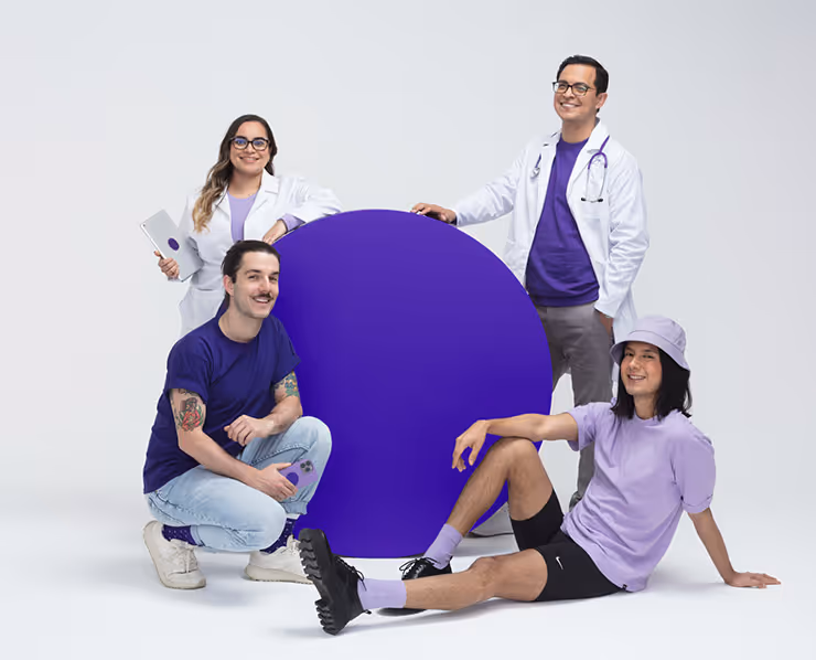 Grupo de jóvenes y profesionales de la salud posando juntos alrededor de un círculo morado, sobre fondo blanco, representando inclusión y bienestar.