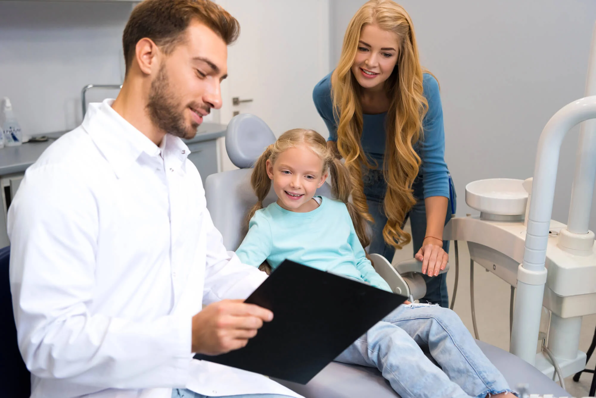 Dentist showing chart to girl and mother, family dentistry in Colorado Springs