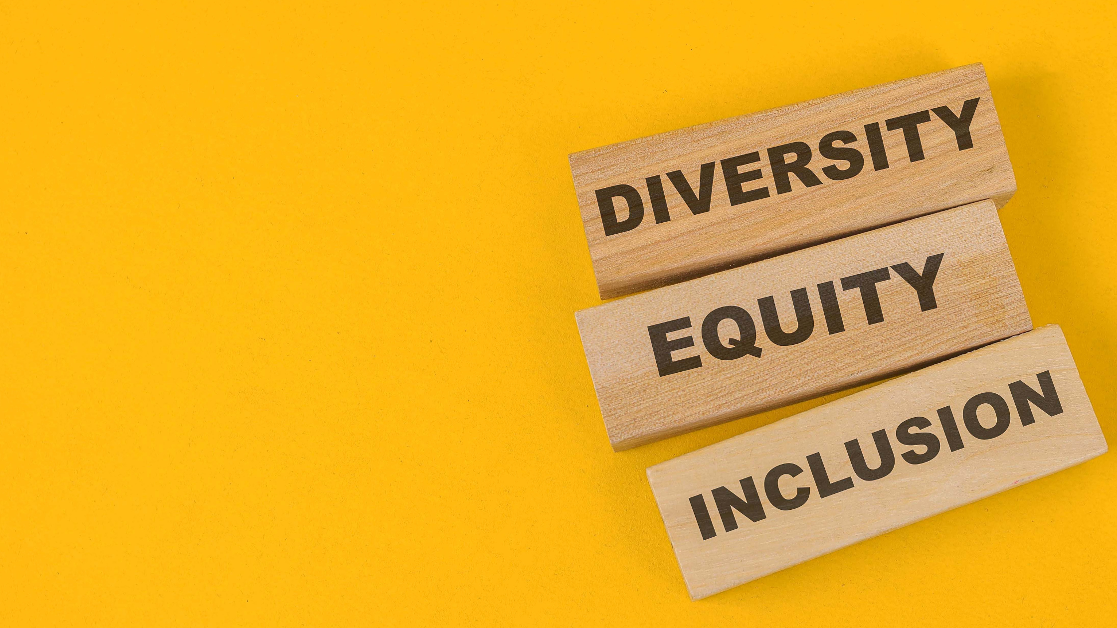 A bright yellow background with light brown blocks spelling out "diversity, equity, and inclusion."