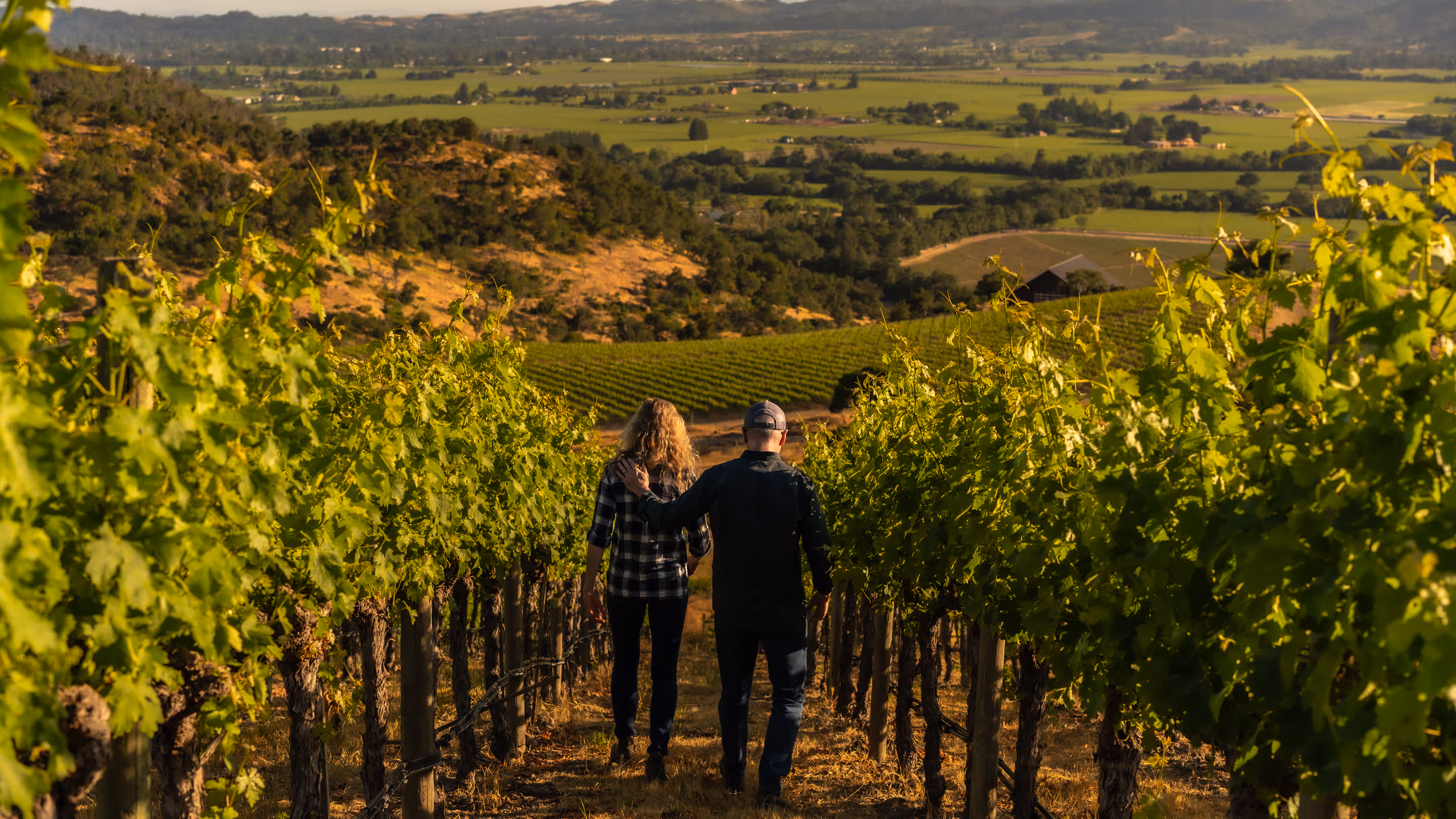 Mike and Schatzi in front of a Husic vineyard row at golden hour.
