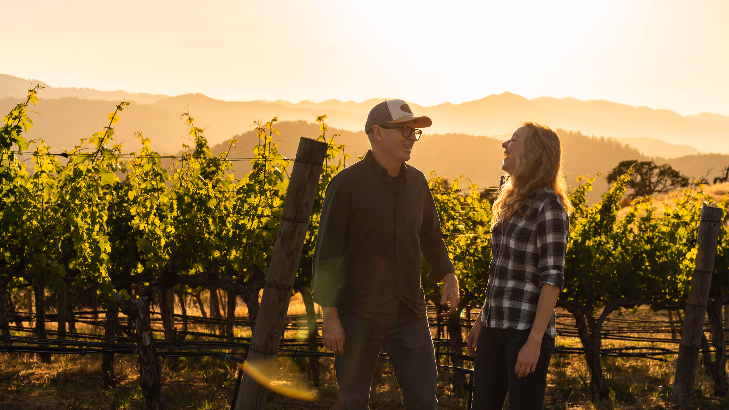 Mike and Schatzi in front of a Husic vineyard row at golden hour.
