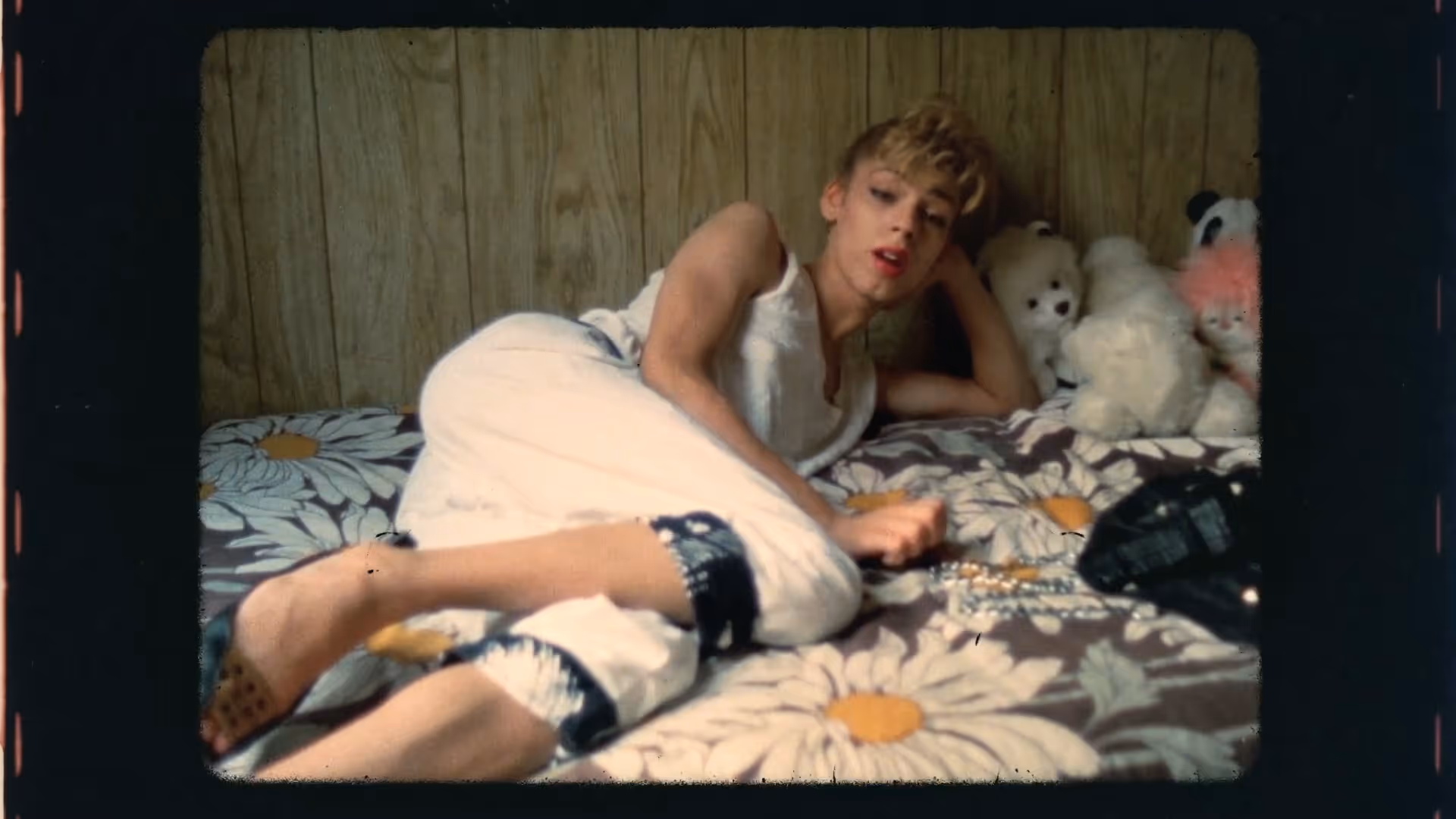 A woman lying on a bedspread with huge daisies design on the bedspread