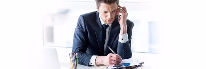 Stressed man on the phone writing on paper