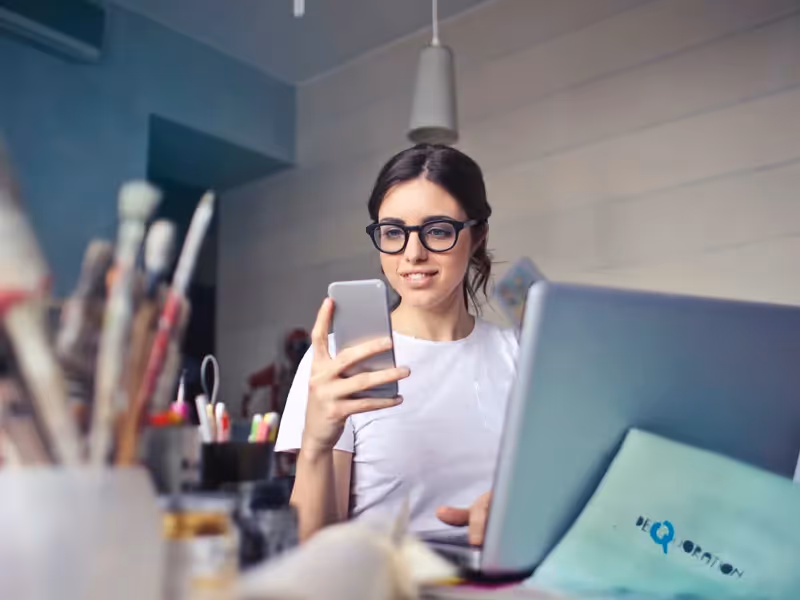 Woman at home on phone with laptop
