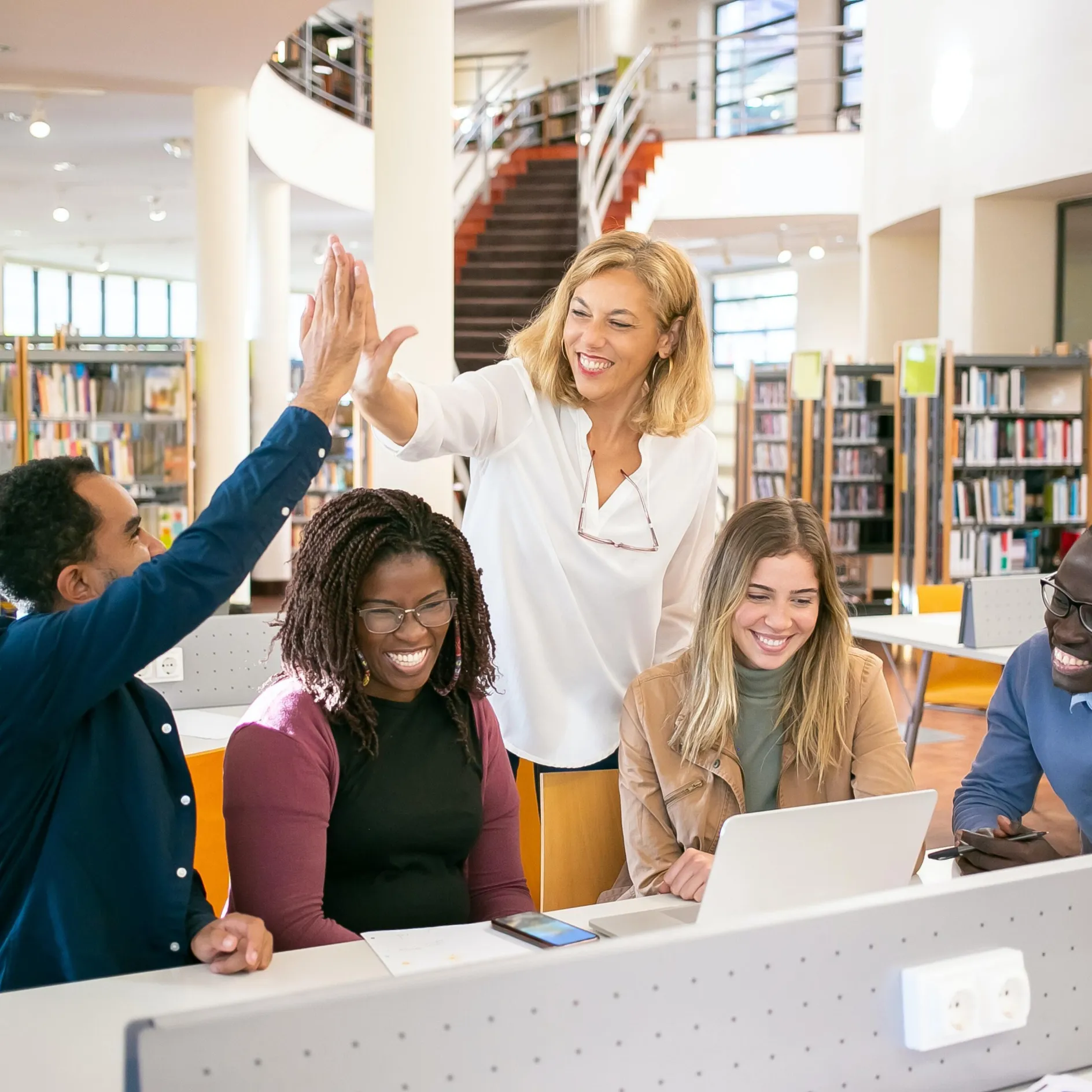 a group of people standing around a laptop computer