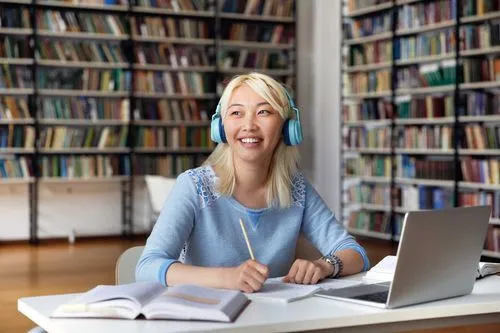Student in library with headphones and smiling