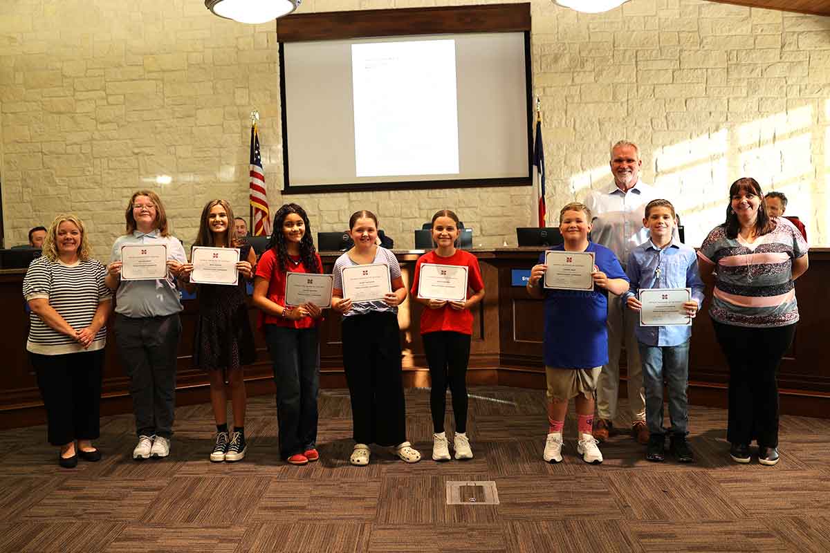 Students receiving award certificates at school board meeting