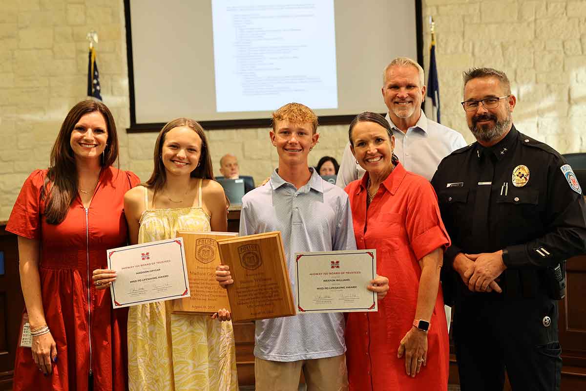 Students receiving award certificates at school board meeting