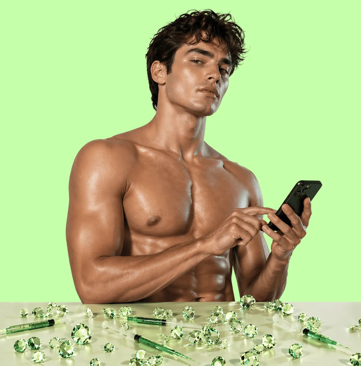 Muscular shirtless man with curly hair using phone, with green syringes and gems on table in front.