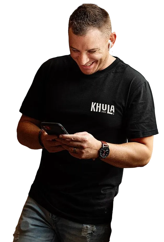 Jamie in a black KHULA shirt looking at his cell phone.